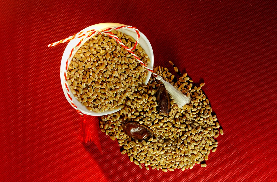 A bowl full of wheat grains dropped over a red table flag