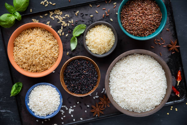 Variety of rices in bowls, with red rice, black rice, basmati, whole grain rice, long grain parboiled rice and arborio rice