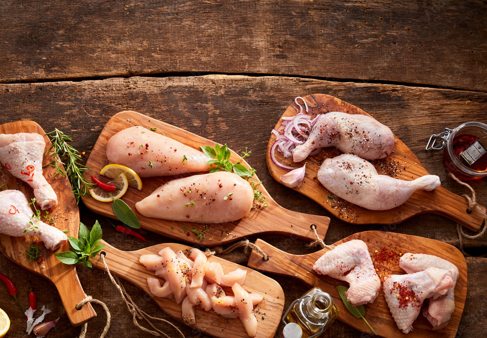 raw fresh seasoned chicken parts on wooden meat board in widescreen