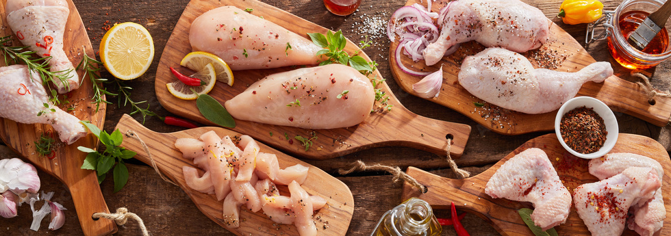 raw fresh seasoned chicken parts on wooden meat board in widescreen