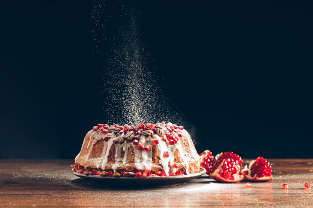 homemade christmas cake traditional homemade christmas cake with pomegranate powdering with icing sugar making powdered sugar stock pictures, royalty-free photos & images