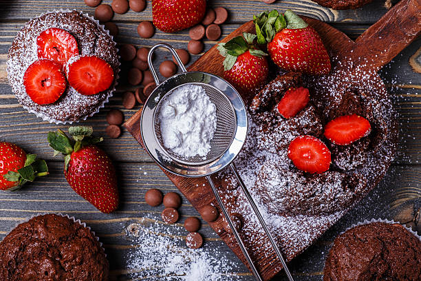 Chocolate muffins with strawberry on dark background. Chocolate muffins with strawberry on dark background, selective focus. powdered sugar making stock pictures, royalty-free photos & images