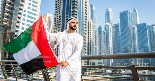 Middle-eastern young adult wearing kandora walking outdoors in Dubai - Arabic man wearing the traditional emirates clothes