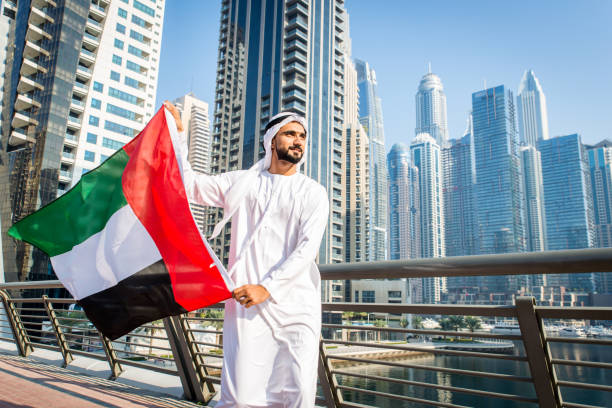 Middle-eastern young adult wearing kandora walking outdoors in Dubai - Arabic man wearing the traditional emirates clothes