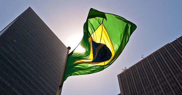 Brazilian National Flag against Skyscrapers by Sunset.