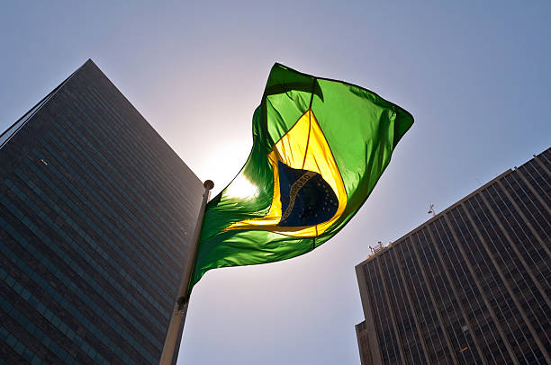 Brazilian National Flag against Skyscrapers by Sunset.